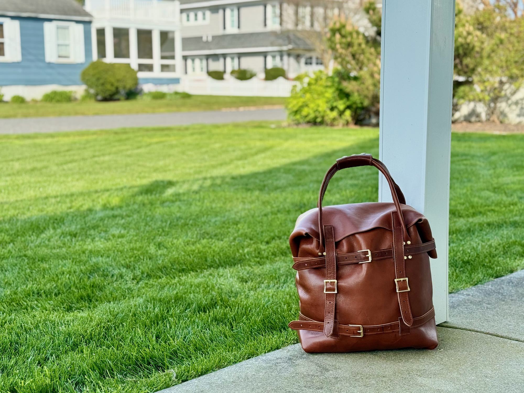 The Strathmere - Leather Weekend Bag - Shown gracefully resting on the porch of a beach house